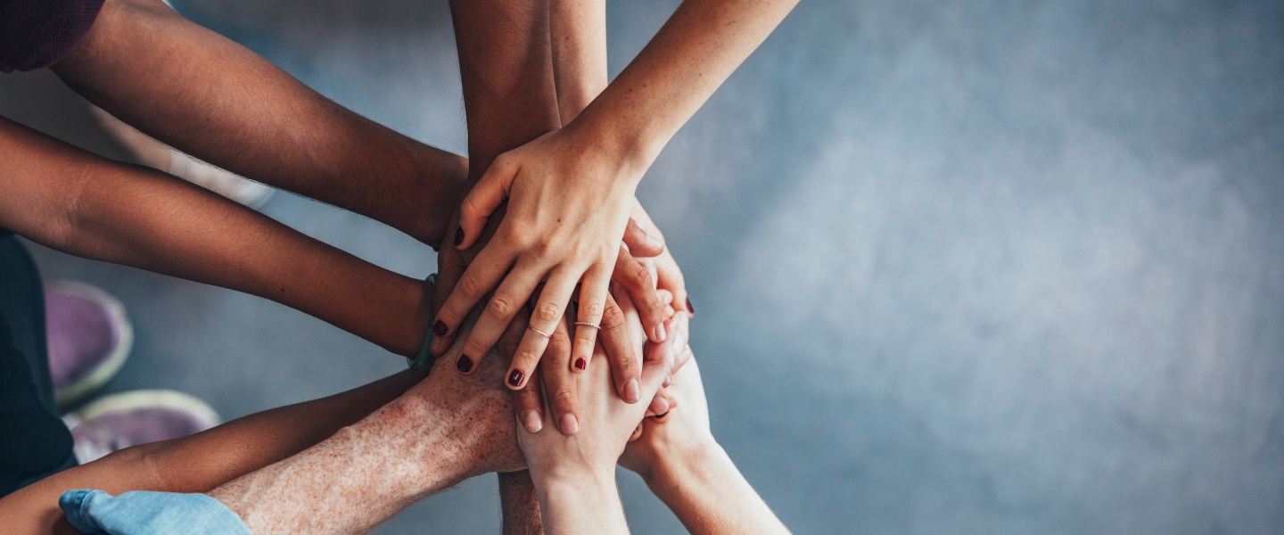 group of hands put together on top of one another in a circle