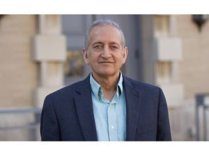 Jainendra Jain stands for a photo in a navy blue blazer and light blue button up.